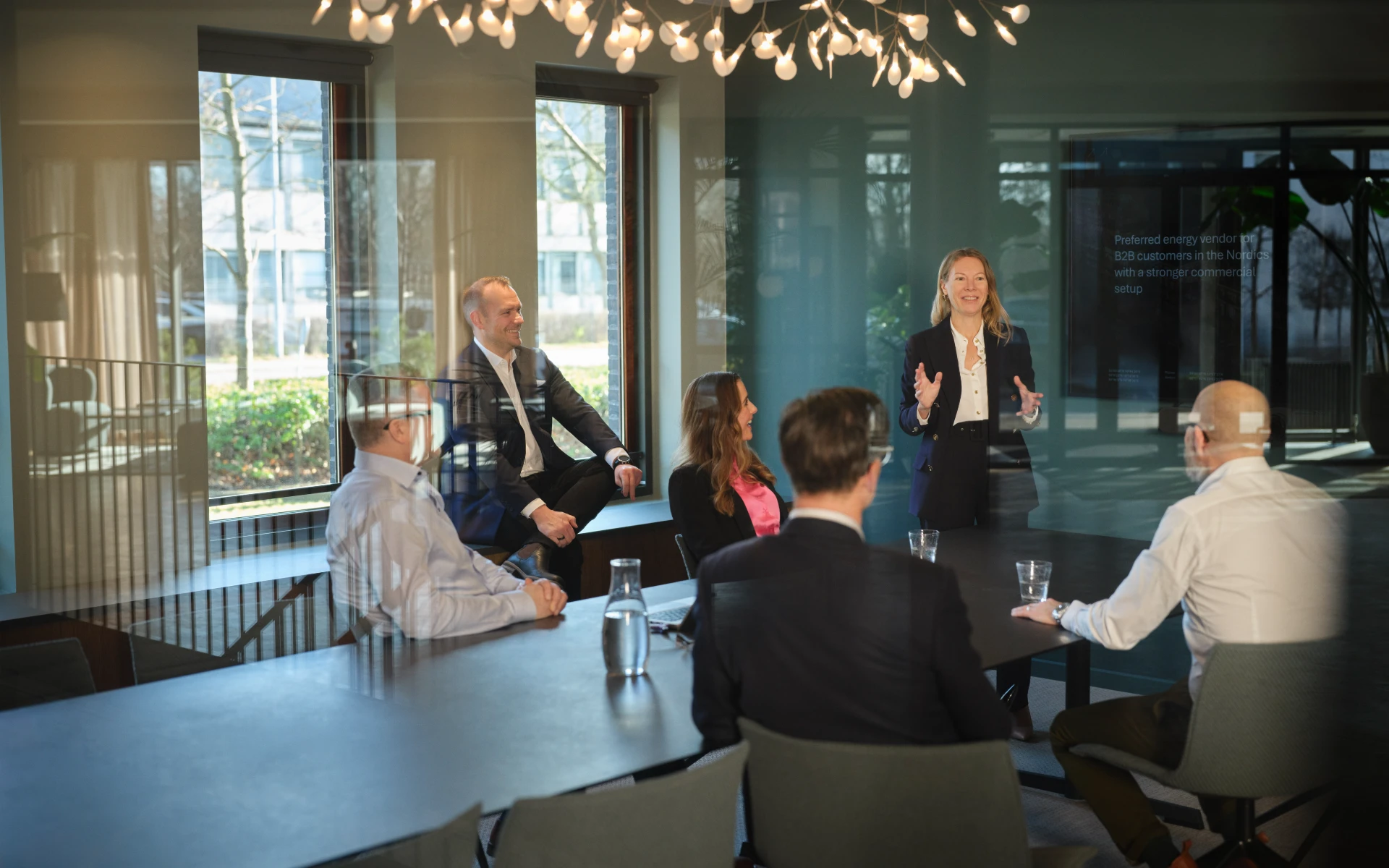 Woman leading a meeting in a modern energy company boardroom with colleagues seated around the table.