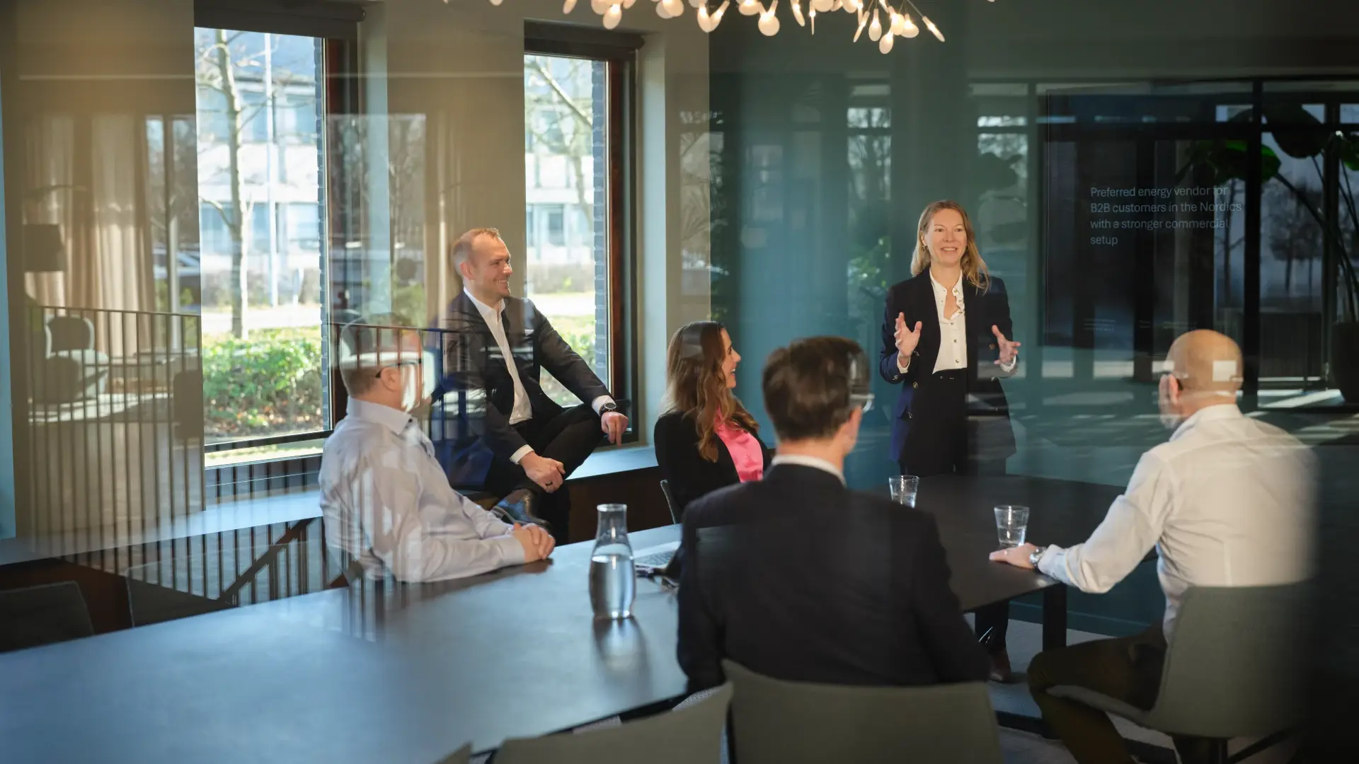 Woman leading a meeting in a modern energy company boardroom with colleagues seated around the table.