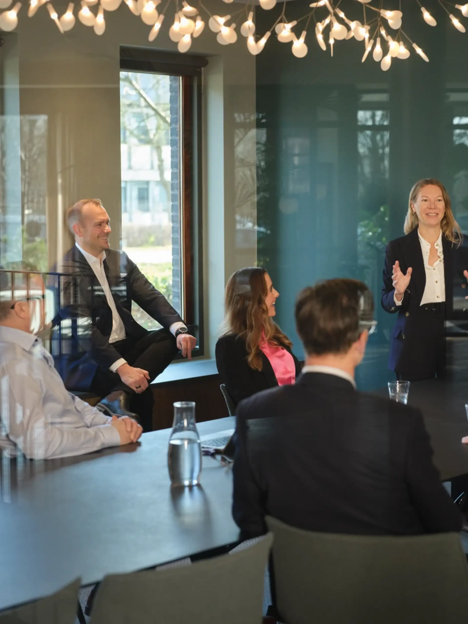 Woman leading a meeting in a modern energy company boardroom with colleagues seated around the table.