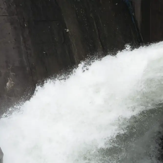 Close-up of water gushing through a concrete sluice gate in a hydroelectric power station.
