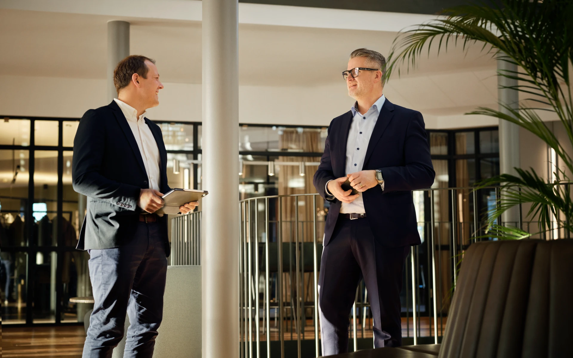 Two men in business attire having a conversation in a bright and modern B2B energy office