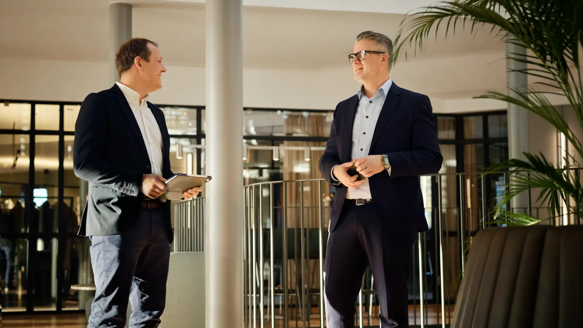 Two men in business attire having a conversation in a bright and modern B2B energy office