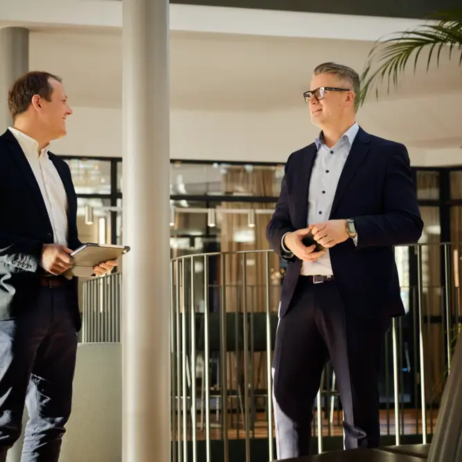 Two men in business attire having a conversation in a bright and modern B2B energy office