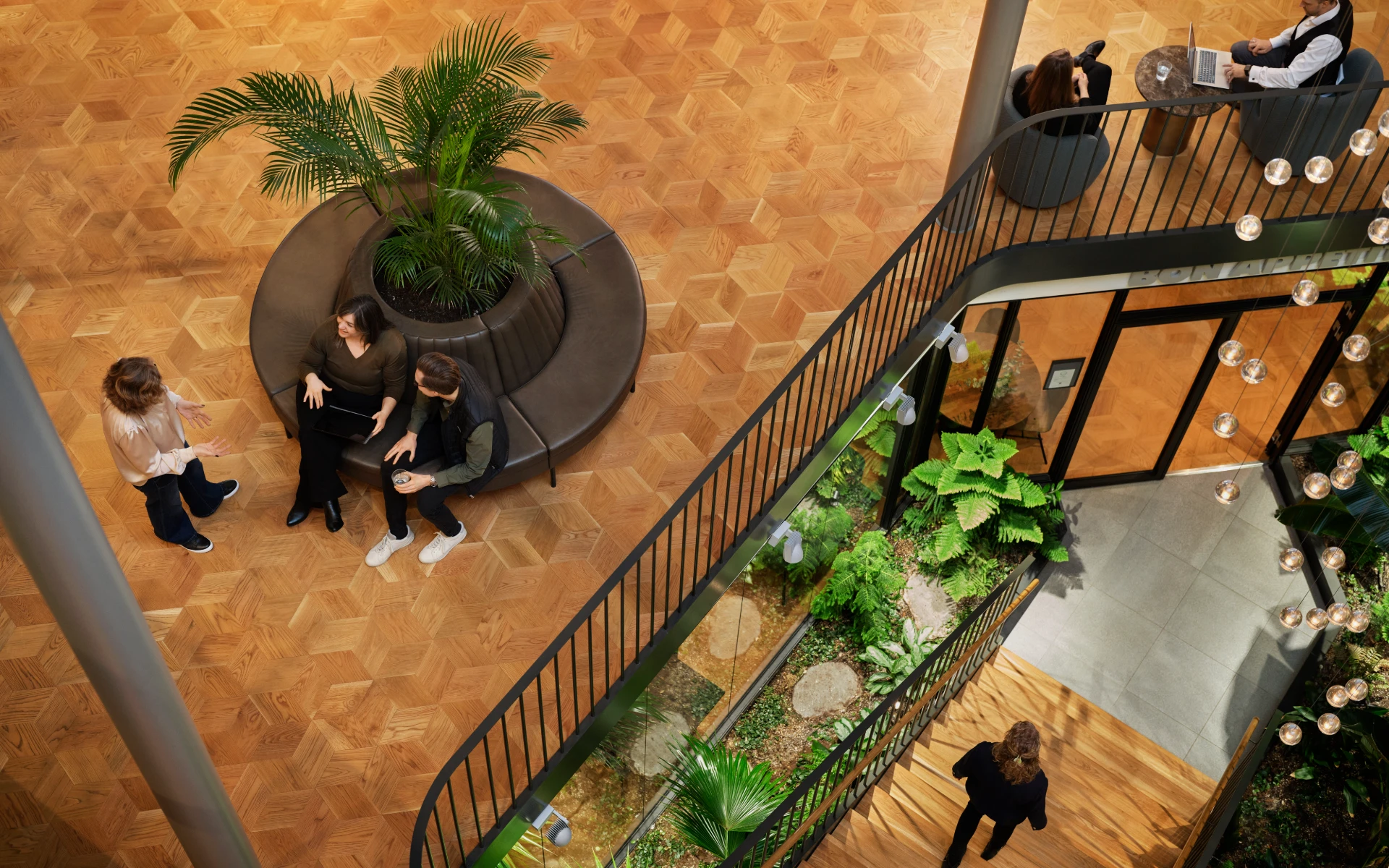 Office atrium seen from above with small groups of people in conversation.