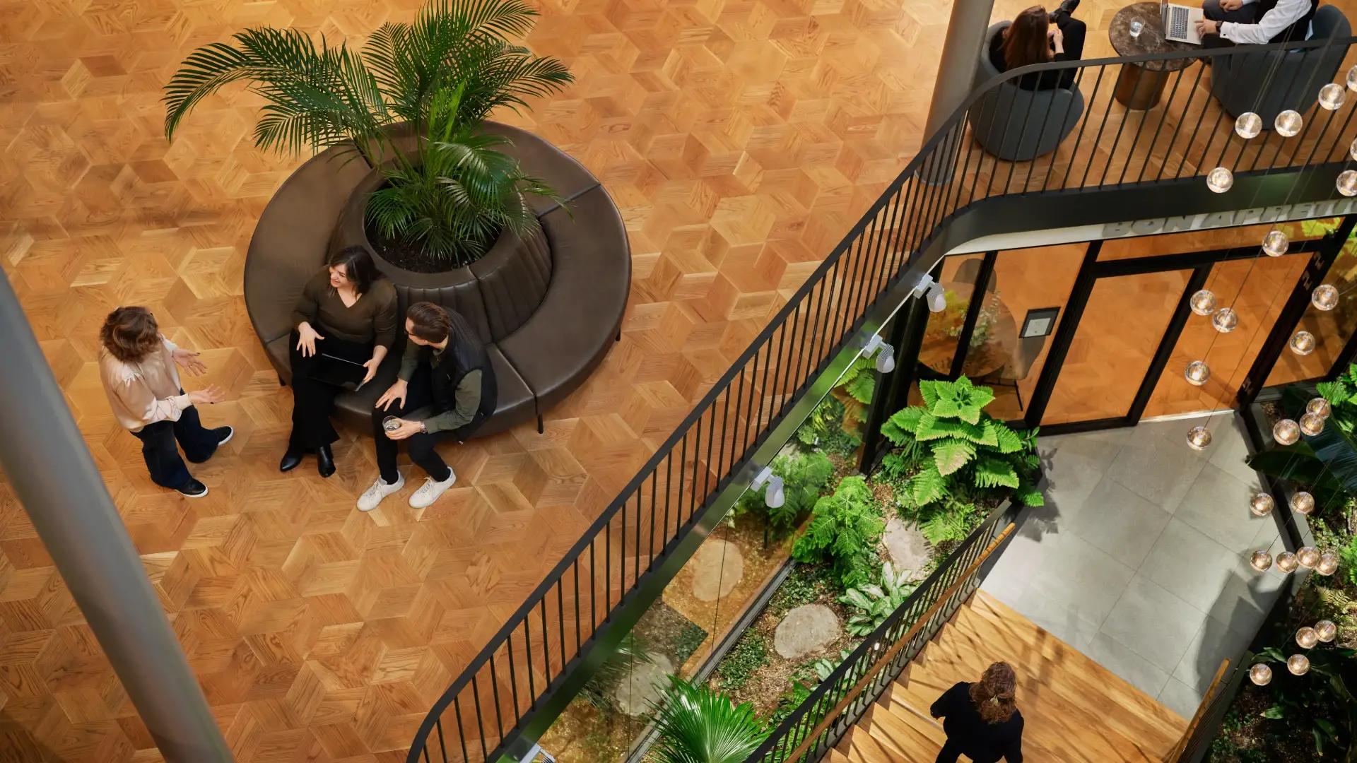 Office atrium seen from above with small groups of people in conversation.
