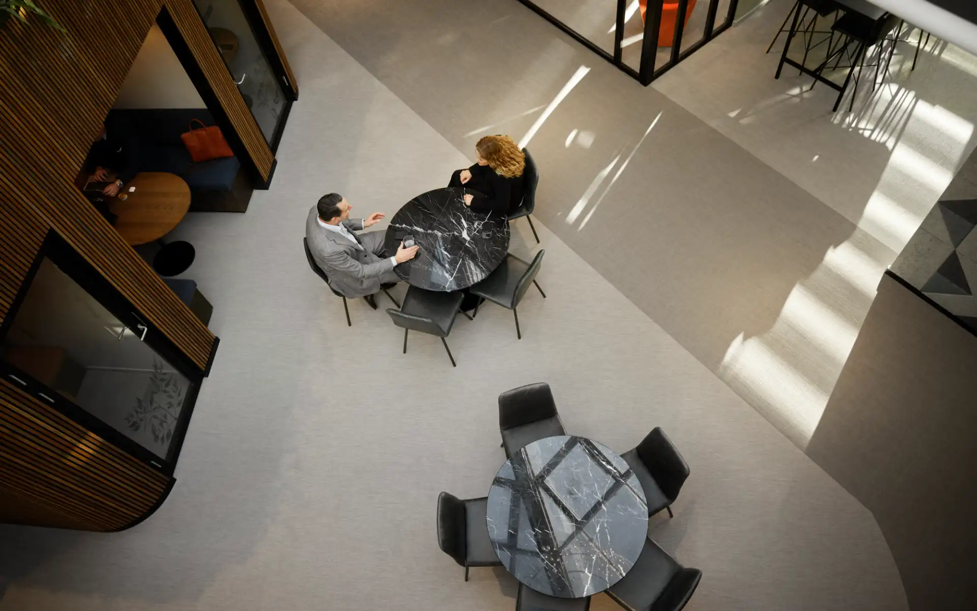 Overhead view of two professionals in conversation at a round table in an energy consulting office.