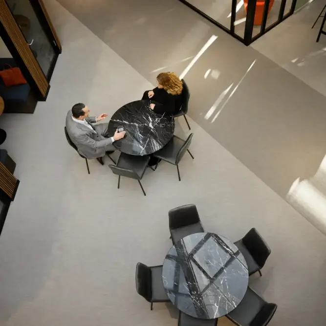 Overhead view of two professionals in conversation at a round table in an energy consulting office.