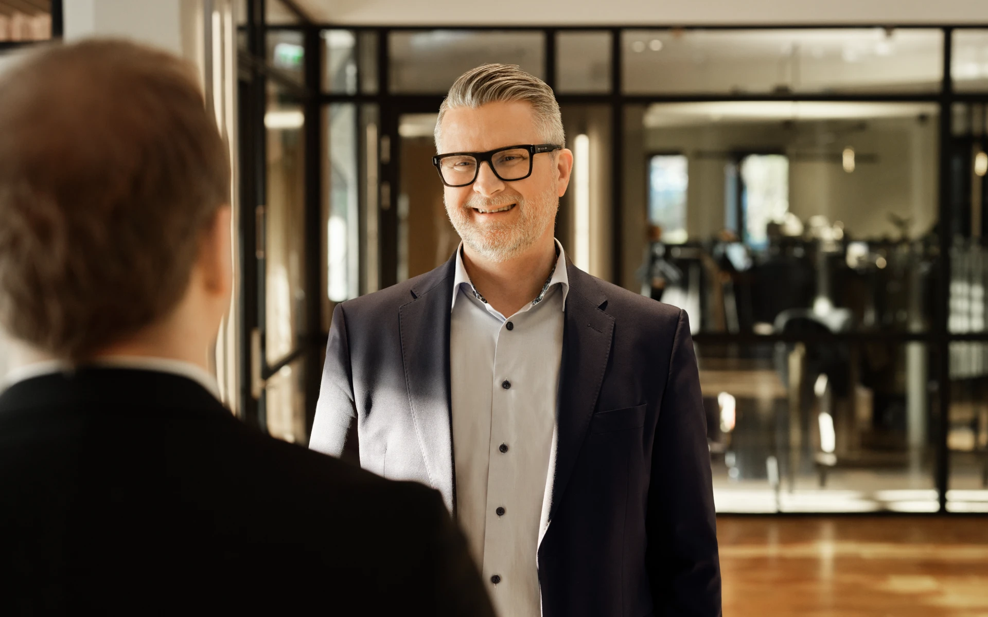 Man smiling during a conversation in a hallway of a B2B energy solutions company.