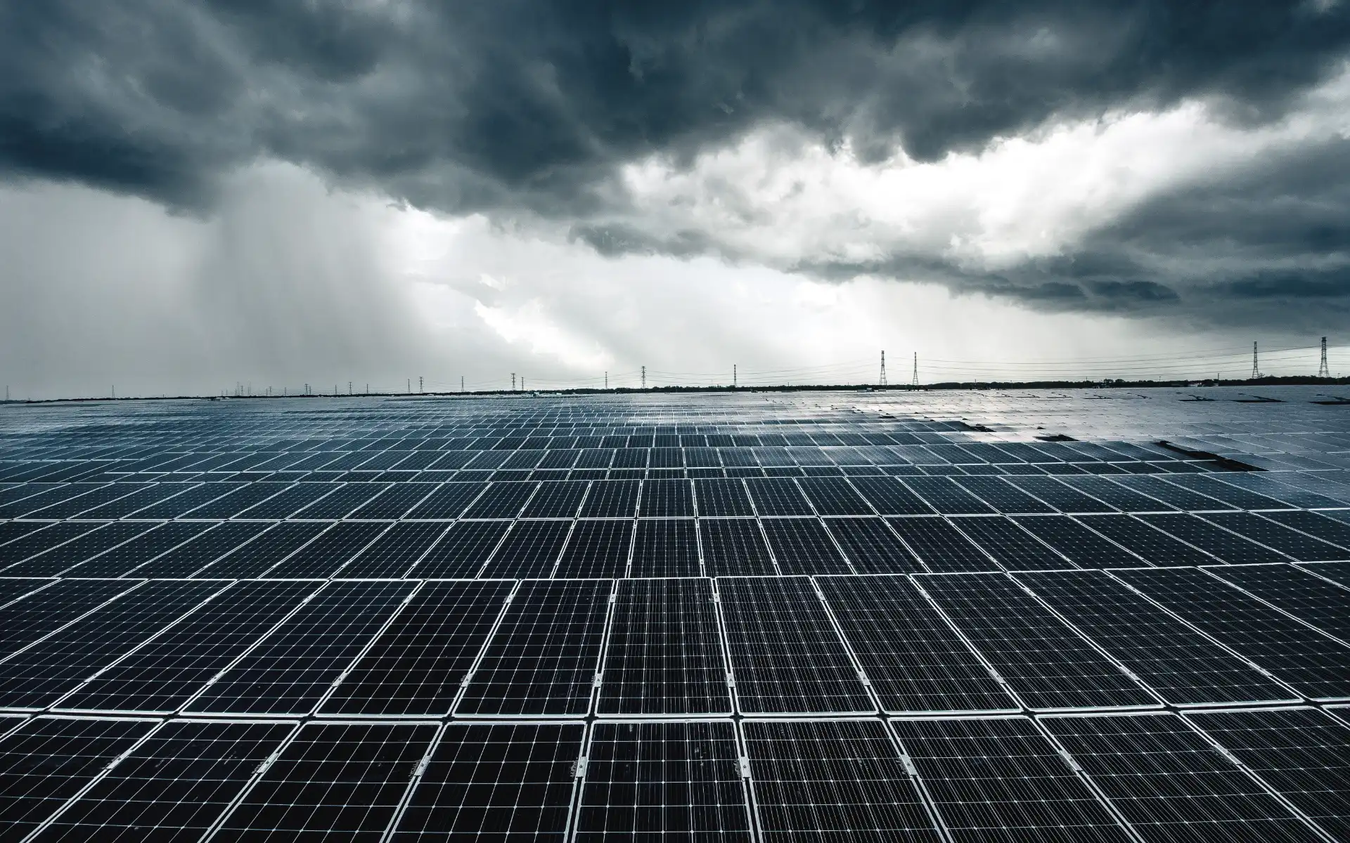 Large solar farm with rows of panels under a dramatic, cloud-filled sky.