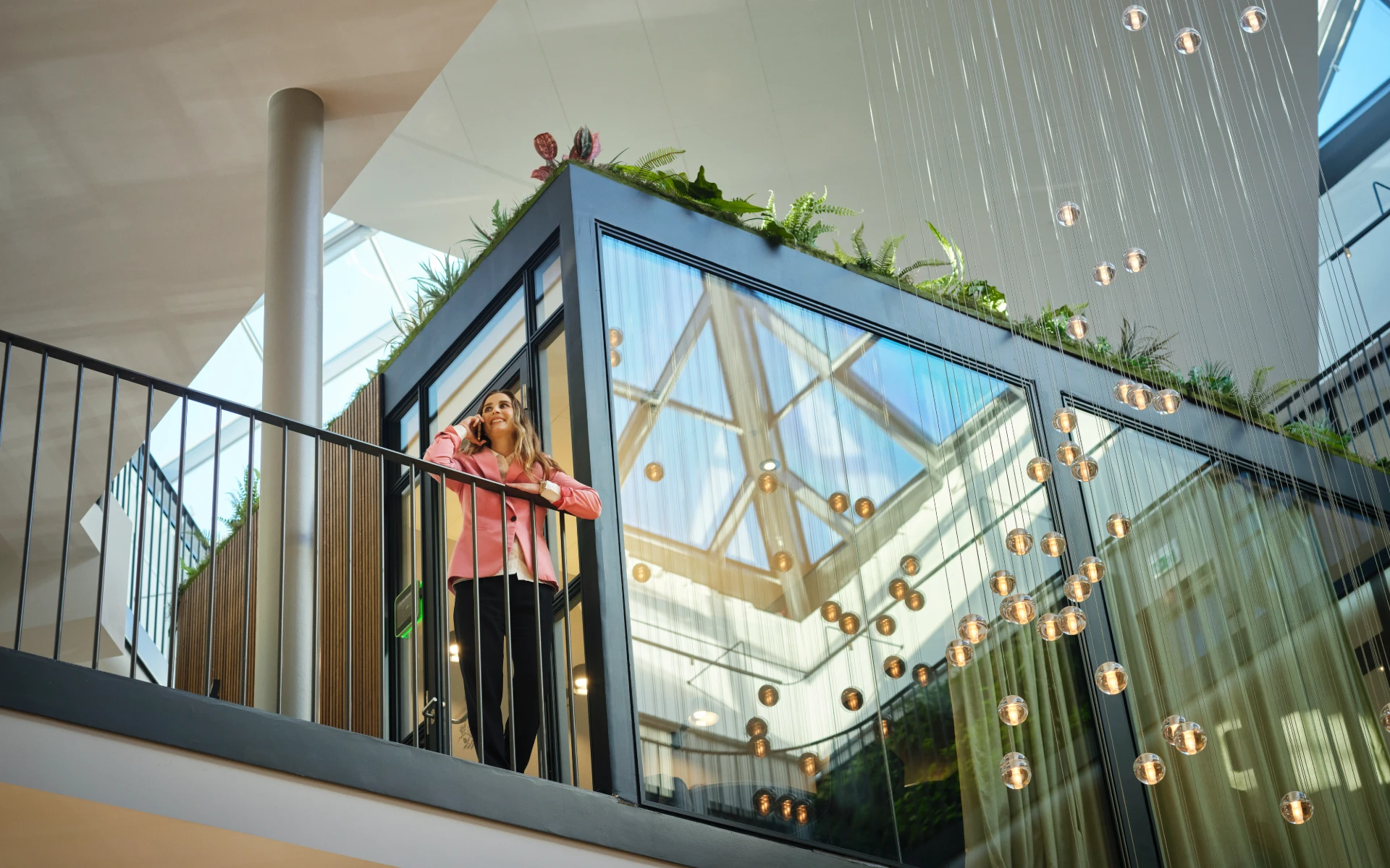 Business professional taking a phone call on an office balcony in a sustainable energy company’s atrium