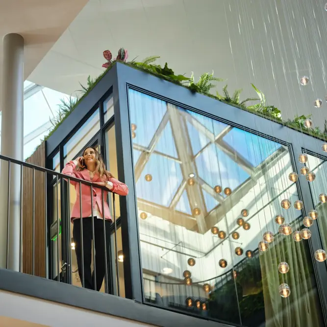 Business professional taking a phone call on an office balcony in a sustainable energy company’s atrium