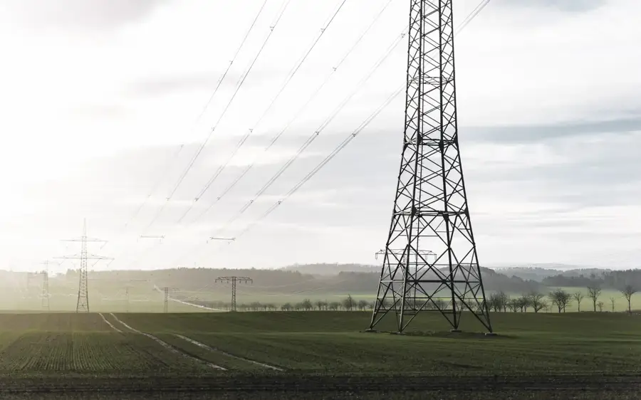 High-voltage transmission towers and power lines stretching across a green rural landscape.