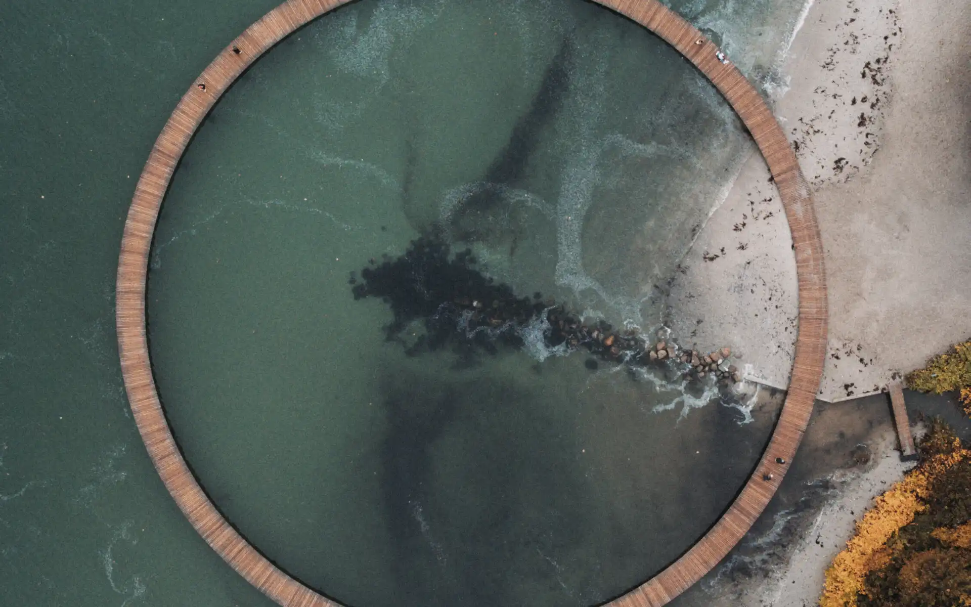Aerial view of a circular coastal boardwalk over green sea water, symbolizing sustainability, circular economy, and innovative energy pathways.
