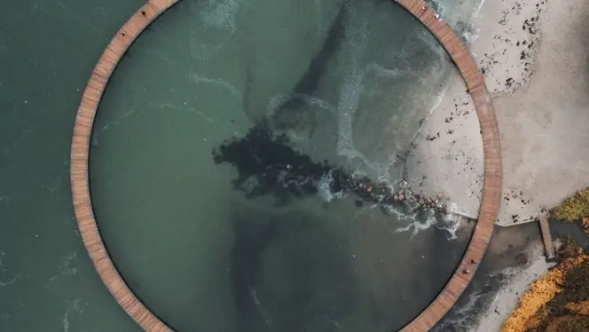 Aerial view of a circular coastal boardwalk over green sea water, symbolizing sustainability, circular economy, and innovative energy pathways.