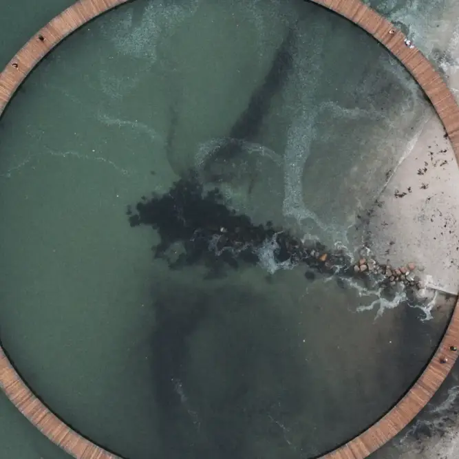 Aerial view of a circular coastal boardwalk over green sea water, symbolizing sustainability, circular economy, and innovative energy pathways.